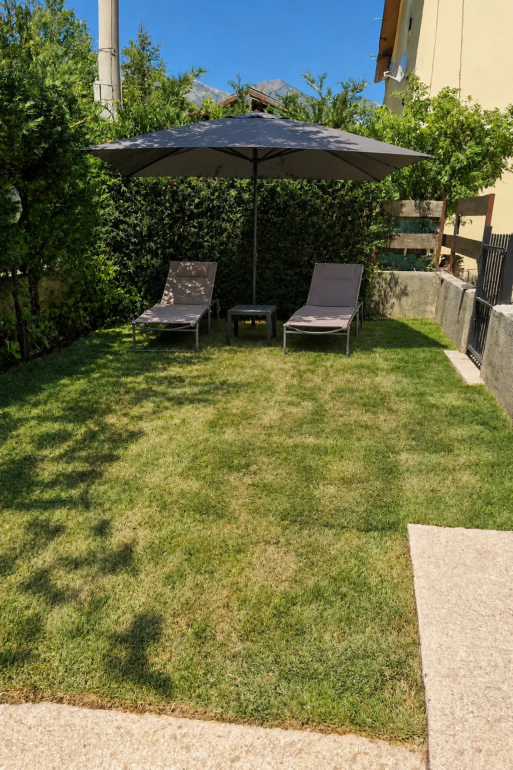 Il giardino con due lettini e ombrellone